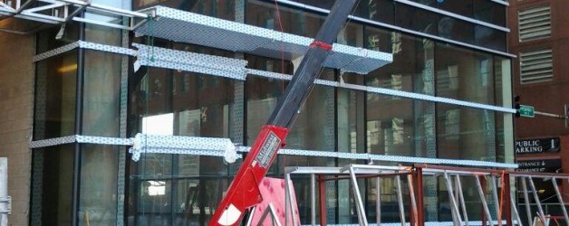 Spydercrane installing glass in building